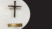A brown cross on a white wall with a plaque entitled 'Coventry' underneath