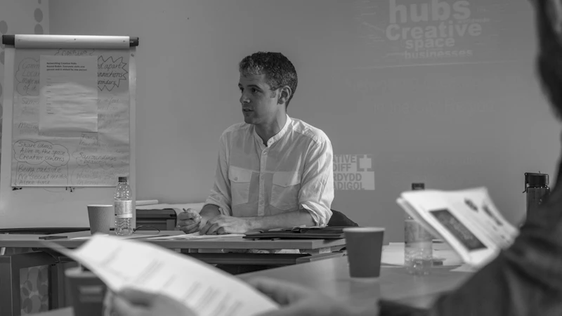 Johann Gregory sitting at a seminar table beside a flip-chart