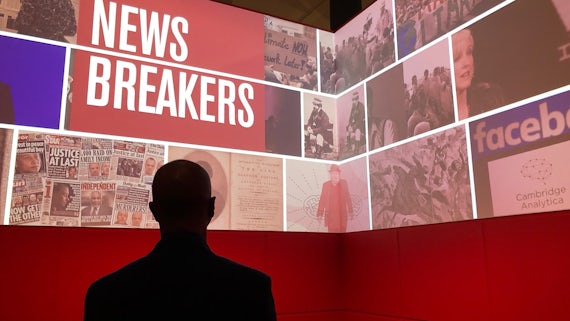 Silhouette of a man in front of a wall display of news images