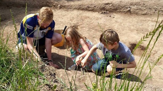 A man and two children taking part in a dig.