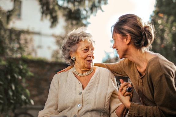 An older woman and young woman sitting closely and speaking at a table