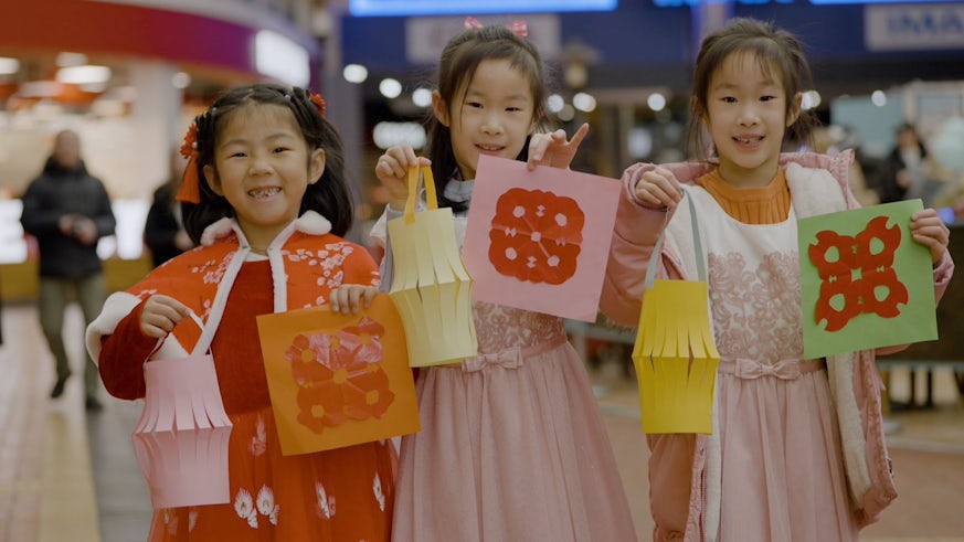 Three children showing their paper-cutting at the Red Dragon Centre's Chinese New Year event