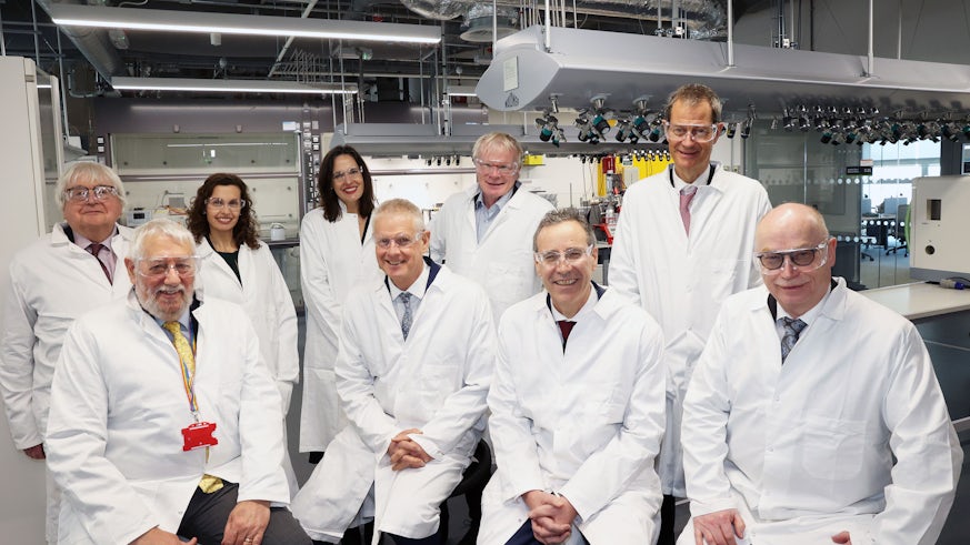 Two rows of people wearing lab coats are photographed in a laboratory in Cardiff University’s Translation Research Hub