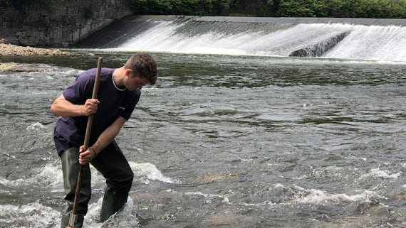 Student completing kick-sampling in a river