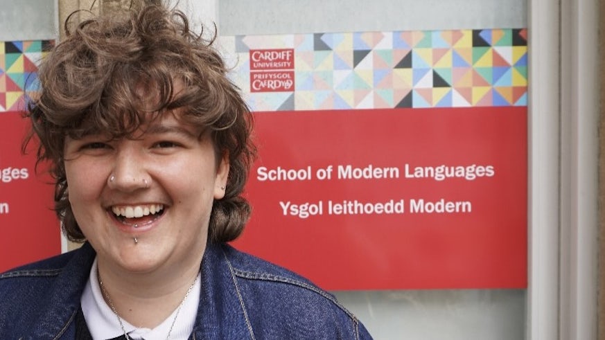 person standing in front of a sign which says School of Modern Languages.