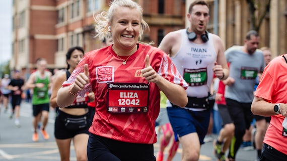 A woman in red running kit runs a half marathon