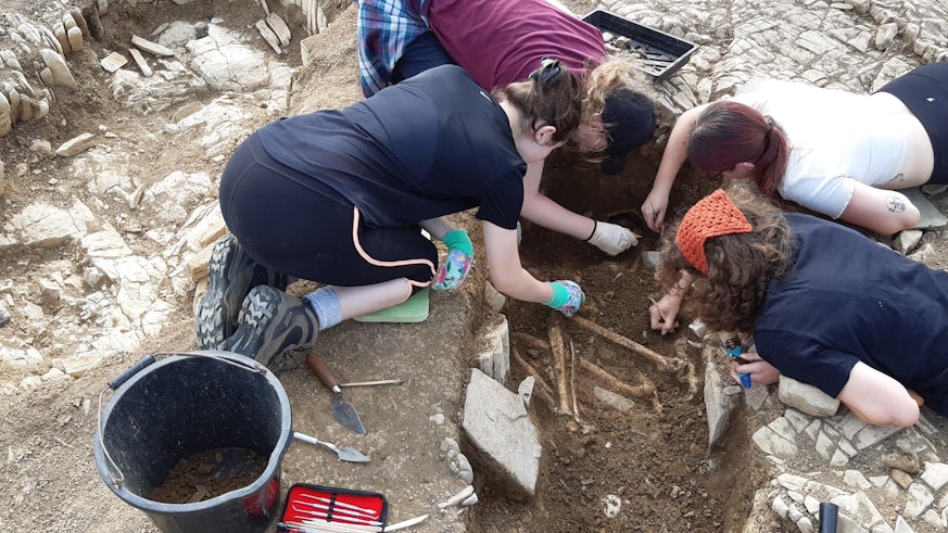Students surrounding grave and excavating the area