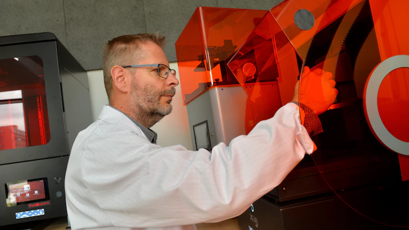 Man in a white jacket using 3D printing equipment