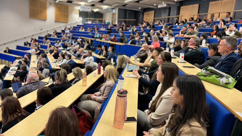 Lots of people sat listening in a lecture theatre