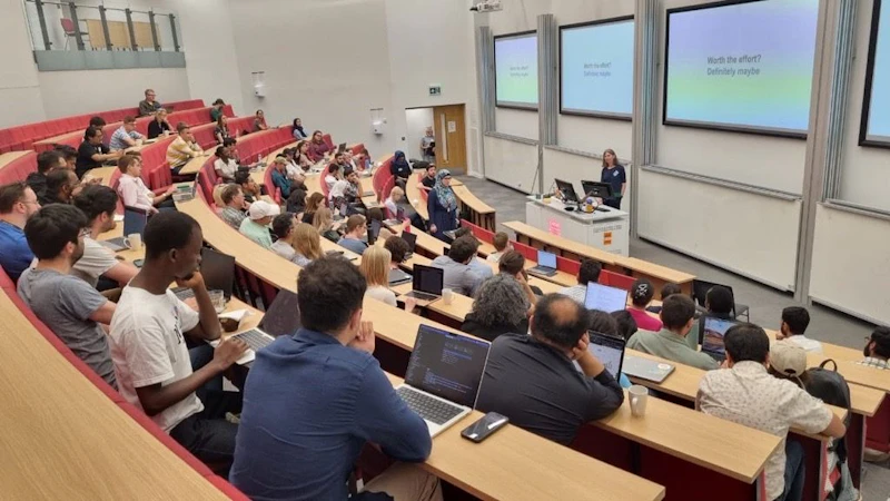 A group of people watch a talk given at Cardiff NLP Summer Workshop 2025