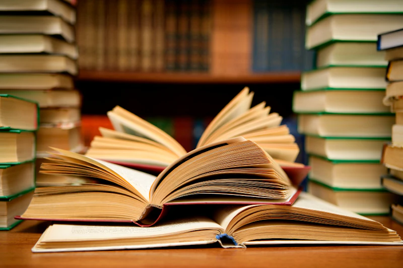 Stacks of open books sitting on a library table.