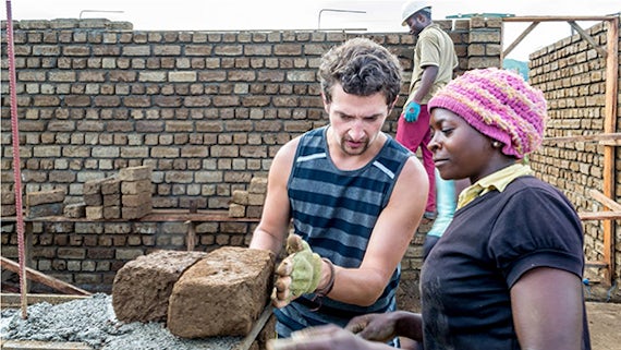 Student demonstrating construction techniques to a local woman