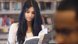 A femail student reads a book in a library