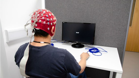A male participant with electrodes attached to his head carries out a computer task