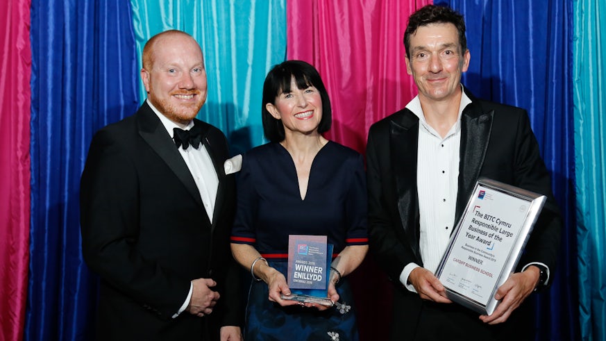 Three people posing with award