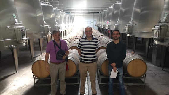 Three men in wine production facility