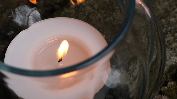 A lit candle in a small glas holder