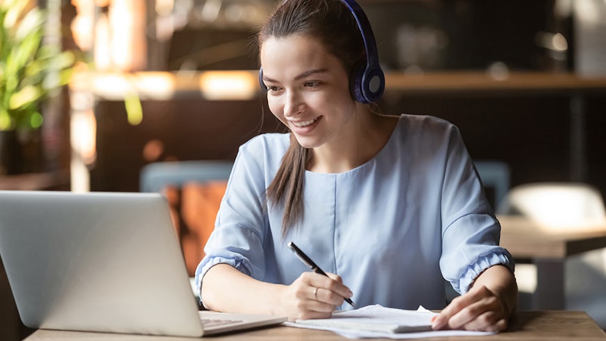Smiling girl student wear wireless headphone study online with skype teacher