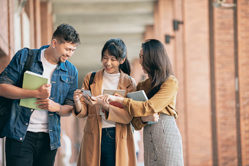 three diverse students look at phone together