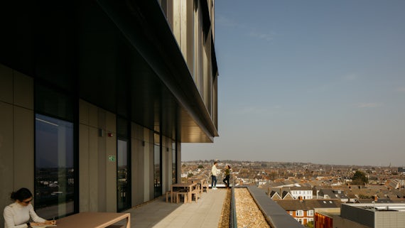 People working on the balcony at spark looking over the blue sky and Cardiff
