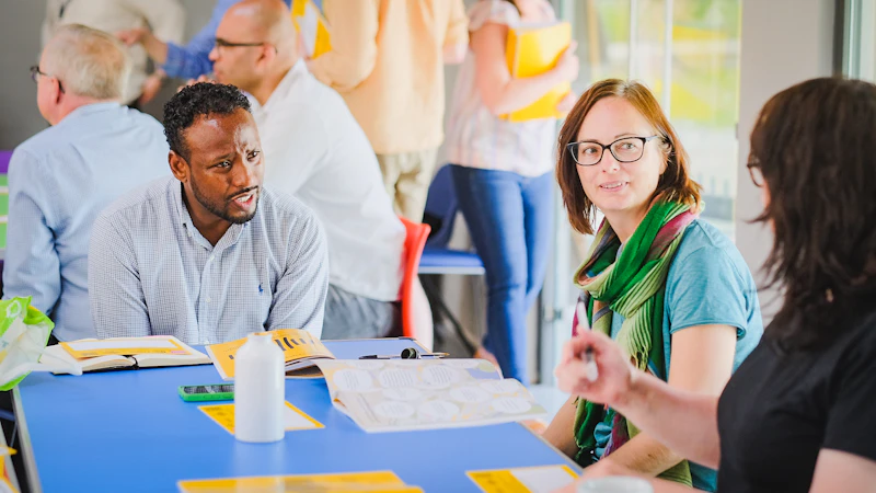 A man speaking with two women around a table in one of the meeting rooms at the Grange Pavilion.