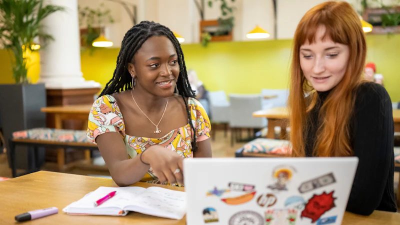 Two students looking at a laptop screen