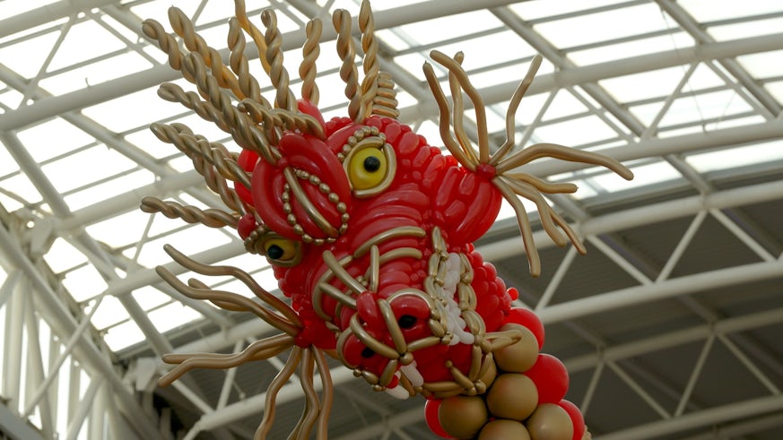 The head of a red and  gold dragon made out of balloons.
