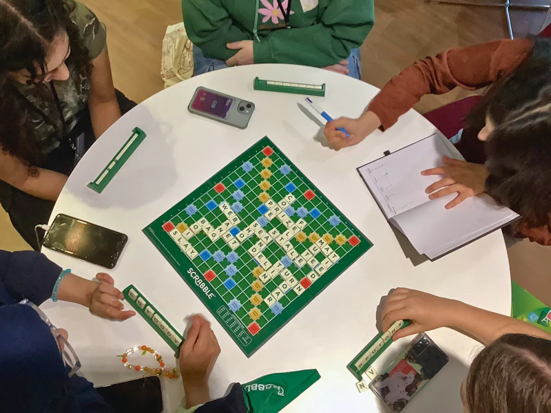 Students sitting around a table playing a game of Scrabble as part of a Step Up summer school activity.