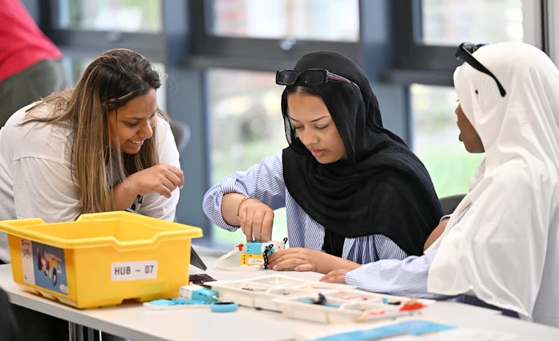 Participants working with small robotics or engineering kits during a Step Up summer school workshop.