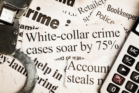 Handcuffs and calculator on headlines about white collar crime