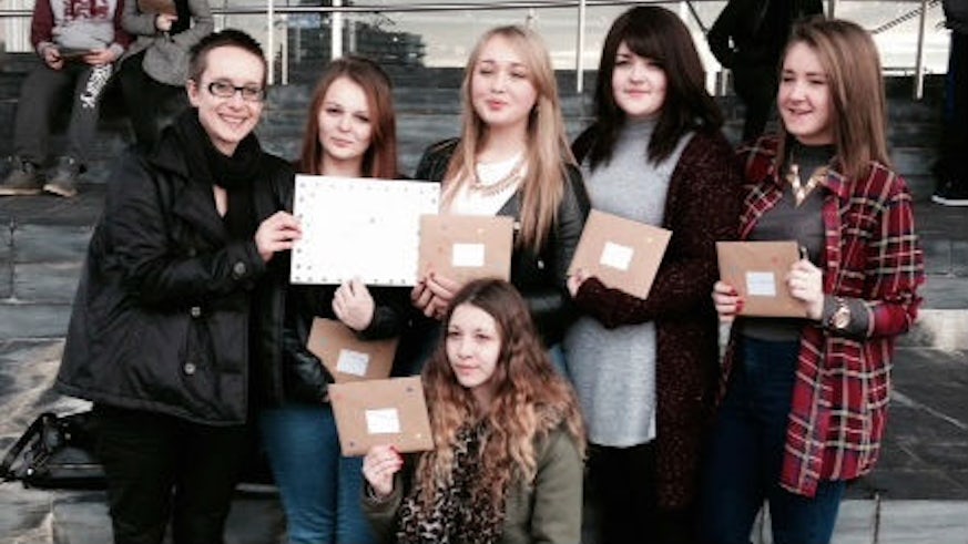 Female students standing outside the Senedd in Cardiff Bay, holding Valentine cards for an anti-abuse campaign