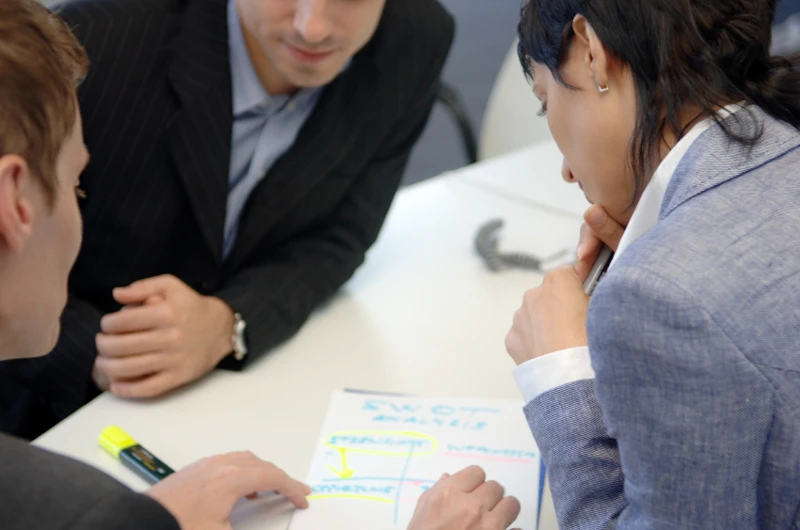 Close up of three business people gathered round a table