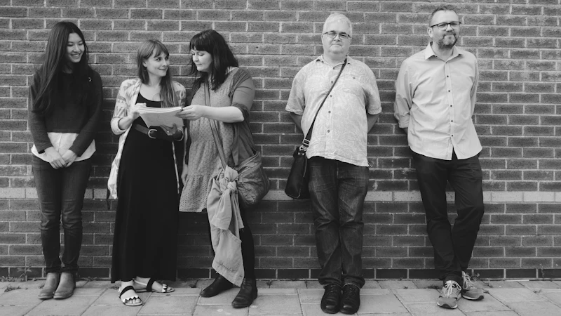 Members of the Love Grangetown project team lean against a brick wall