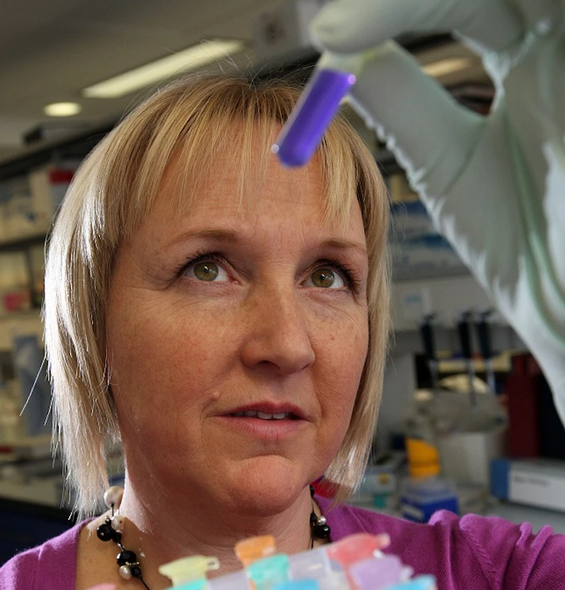 Photo of a lady holding up and examining a test tube