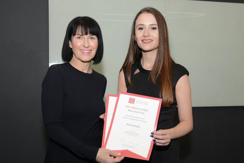 Two women pose with certificates