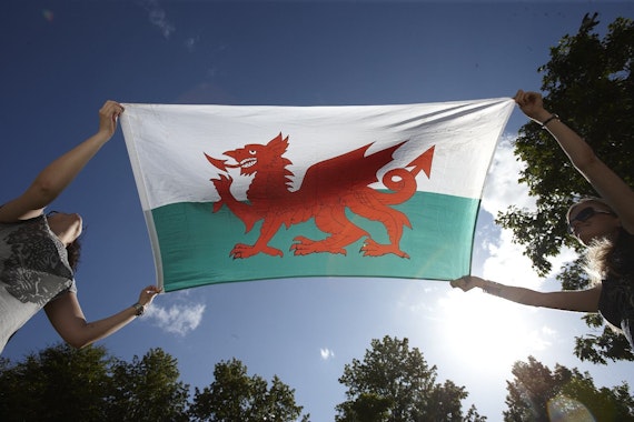 Welsh flag behind held by two people 