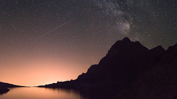 Shooting star over a mountain range and lake