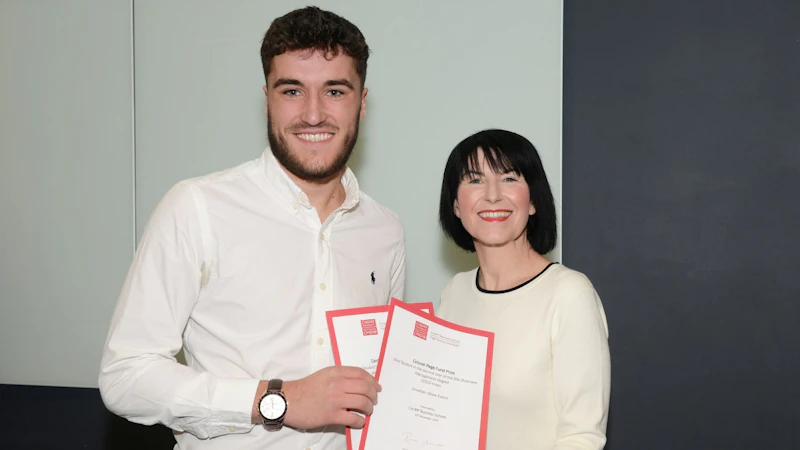 Male student collects two awards from Dean