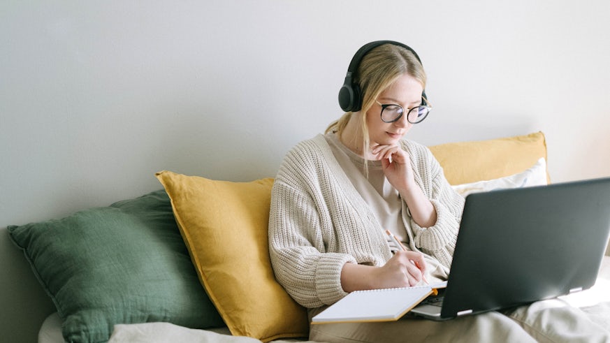 Blonde woman wearing headphones on laptop