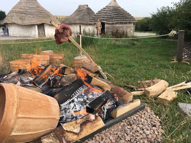 Meat and pots cooking over an open fire.