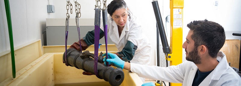 Cannon being lifted by two people in white coats