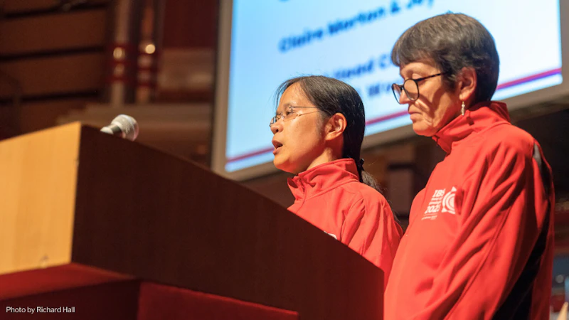 Professor Joy Myint from the school of Optometry at the Blind Games standing at a podium with a colleague