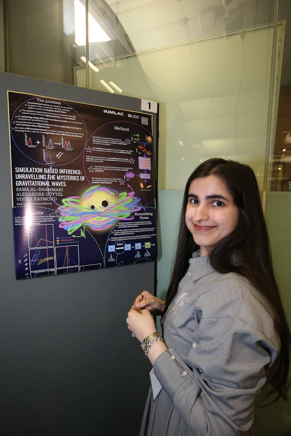A young woman poses for a photograph alongside a poster about her research on gravitational waves.