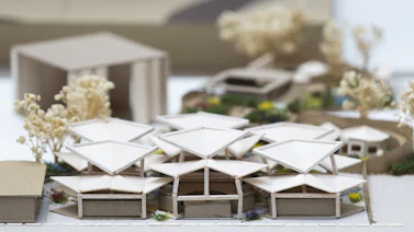 A model, made of cardboard, of a small collection of dwellings with triangular roofs