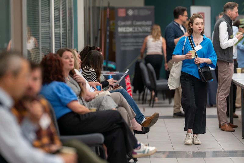 At the CUIN Digital Health in Wales event, people sat to network whilst a lady walked by next to them.