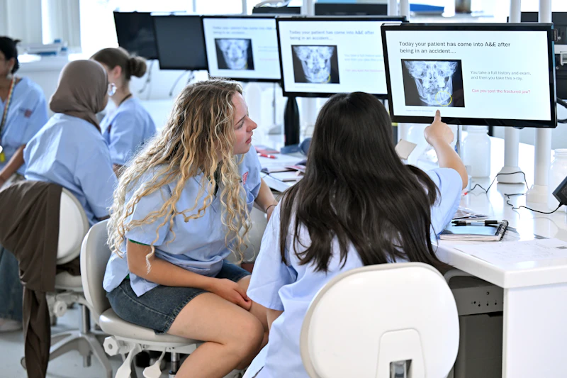 Participants in clinical uniforms working at computer stations during a dentistry‑themed workshop.