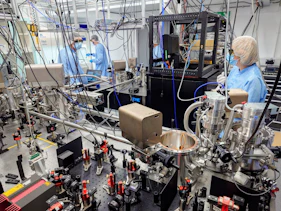 A team of scientists are photographed in the lab wearing PPE conducting an experiment with lots of technological equipment including lenses, mirrors and lasers.