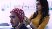 Woman attaching an EEG cap and electrodes to a male study participant's head