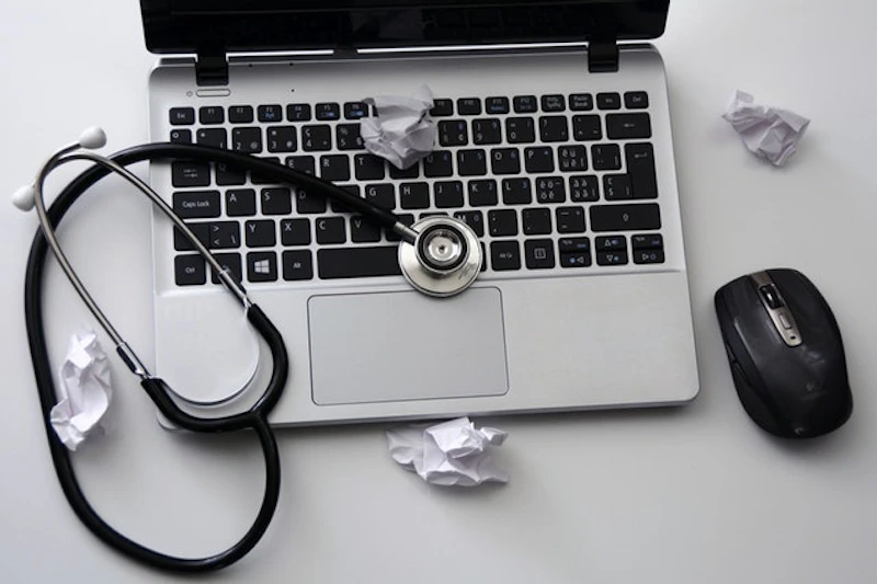 A stephoscope across a laptop with pieces of paper