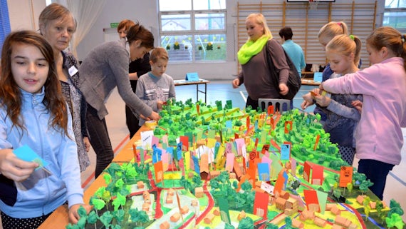 Children and women clustered around a model of a neighbourhood